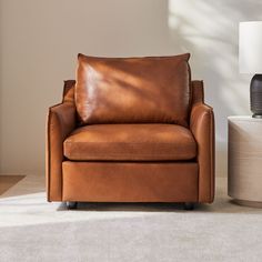 a brown leather chair sitting on top of a carpeted floor next to a lamp