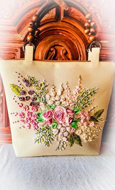 a handbag with flowers on it sitting on a table next to a wooden wall