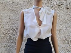 This ivory white sleeveless blouse is essential to any well-edited wardrobe. Laid back yet chic, it's crafted in 100% pure silk with a pleat relaxed shape and flattering / boat neckline. Perfect for event, work or off-duty dressing it will take you through the new season and beyond. * Measurements: Size S  Bust :50 cm ( 20'' in)- laying flat measured from one armpit to the other. Hips :54 ( 21'' in) Long : 56 cm ( 22'' in)- length measurement is taken from top of the front shoulder to hem. Size Elegant V-neck Top With Bow, White Sleeveless Top With Bow, Elegant V-neck Blouse For Summer, Feminine Tie Neck Top For Evening, Elegant Sleeveless Summer Blouse, Feminine Tie Neck Formal Tops, Spring Evening Tops With Tie Neck, Feminine Formal Tie Neck Tops, Feminine Tie Neck Tops For Formal Occasions