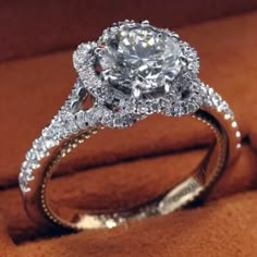 a close up of a diamond ring on a brown velvet surface with an orange background