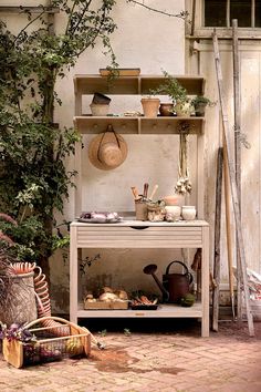 an outdoor kitchen with pots and pans on the shelf, next to a potted plant