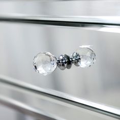 a close up view of the handles on a cabinet door with glass knobs and chrome hardware