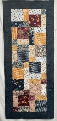 a quilted wall hanging on the side of a bed