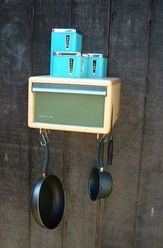 pots and pans hanging from hooks on a wooden wall next to a pot rack