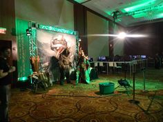 two people standing in front of a stage set up for an event with green lighting