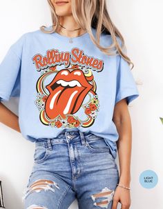 Step back in time and rock out in style with our Vintage Flower Rolling Stone Tee! 🌸🎸 This retro-inspired t-shirt features a classic Rolling Stone logo beautifully intertwined with vibrant flowers, capturing the free-spirited essence of rock 'n' roll and the timeless charm of the 70s. 🌼✨ Crafted from super-soft, high-quality fabric, this tee offers ultimate comfort and a perfect fit, making it an essential addition to your wardrobe. Whether you're heading to a concert, a festival, or just channeling your inner rock star, this tee will have you looking effortlessly cool and totally groovy. 🌟👕 Get ready to roll and bloom with style! 🌿🎶🛒 Spring Fan Merchandise Crew Neck Tops, Spring Fan Merchandise Screen Print Top, Retro Graphic Print T-shirt For Spring, Crew Neck Tops For Spring Music Festival, Spring Crew Neck Tops For Music Festival, Spring Music Festival Crew Neck Tops, Groovy Summer Streetwear Tops, Retro Relaxed Fit T-shirt For Music Festival, Hippie Graphic Print Top For Music Festival