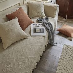 a couch with pillows and a blanket on it in a living room next to a window