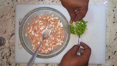 two hands holding a fork over a bowl of food