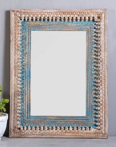 a mirror sitting on top of a table next to a potted plant