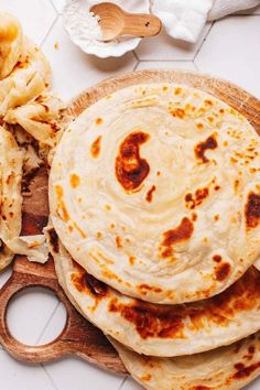 three tortillas sitting on top of a wooden cutting board next to a knife