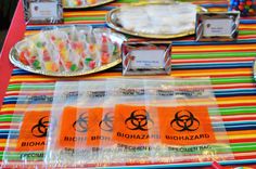 a table topped with lots of candy covered in plastic wrapper next to plates and trays