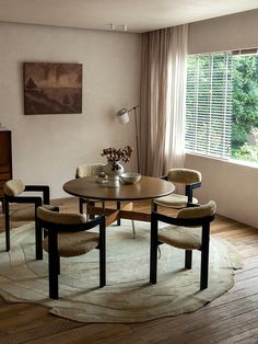 a dining room table with four chairs and a rug on the floor in front of it