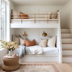 a white bunk bed sitting under a window next to a rug on top of a wooden floor