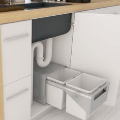 the kitchen sink is open and has two trash cans in it's bottom drawer