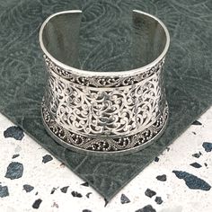 Indulge In The Timeless Elegance Of This Lois Hill Statement Cuff Bracelet. The Center Section Proudly Showcases Lois Hill's Signature Scroll Design, While The Borders Are Adorned With The Intricate Granulated Pattern. The Cuff Edges, Border, And Entire Backside Are All Hammered. Stamped With "Lois Hill" And A Floral Logo Above It At The Center Back, This Bracelet Embodies Authenticity And Artistry. With An Inside Measurement Of Nearly 5.75" And A Gap Of 1.25", The Total Inside Circumference Spans Nearly 7". The Width At The Widest Point, Measured From The Back, Is Just Over 2.125". With A Total Weight Of 123 Grams, This Bracelet Is A Wearable Masterpiece. Product Details: Decade: 20 Luxury Silver Open Cuff Bracelets, Classic Formal Cuff Bracelet With Intricate Design, Classic Intricate Cuff Bracelet For Formal Occasions, Classic Adjustable Cuff Bracelet With Intricate Design, Luxury Wide Band Cuff Bracelet As Gift, Luxury Wide Band Cuff Bracelet Gift, Luxury Silver Open Cuff Bracelet, Classic Cuff Bracelet With Intricate Design As Gift, Classic Intricate Cuff Bracelet As Gift