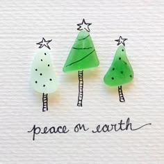 three green trees with stars on them and the words peace on earth written in black ink