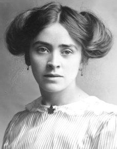 an old black and white photo of a woman with short hair wearing a striped blouse