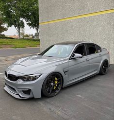 a silver car parked in front of a building with black rims and yellow brake pads