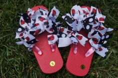 two pairs of red and black flip flops with ladybug bows on them