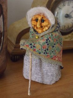 a small stuffed animal with a scarf around it's neck sitting on a table next to a clock