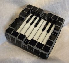 a small black and white piano made out of glass blocks with candles in the middle