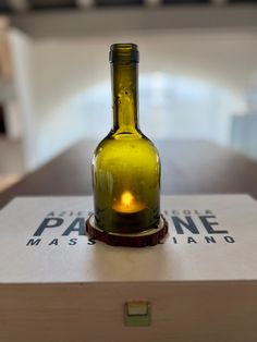 a green bottle sitting on top of a wooden table next to a box with a candle in it