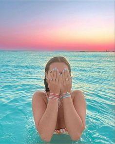 a girl covers her eyes while floating in the ocean