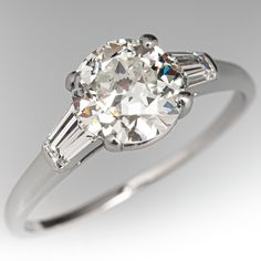 This beautiful vintage ring is centered with one (1) round transitional brilliant cut diamond weighing 1.51 carats that is set into a four-prong setting. The shoulders of the ring are each accented with one (1), channel set, tapered baguette cut diamond. The ring measures 7.6mm at the top, rises 6.2mm above the finger, tapering to 1.1mm wide and 0.9mm thick at the base of the shank. This ring is currently a size 8.75. Luxury Vintage Baguette Cut Jewelry, Circle Diamond With Baguettes, Small Diamond Ring, Baguette Wedding Rings, Small Diamond Rings, Vintage Diamond Engagement Ring, Beautiful Rings Vintage, Rings Vintage, Diamond Engagement Rings Vintage