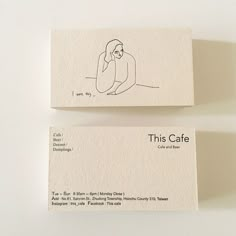 two business cards sitting next to each other on top of a white surface with a drawing of a person