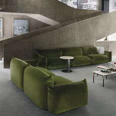 a living room filled with green couches next to a stair case and coffee table