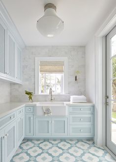 a blue and white kitchen with tile flooring, cabinets and sink in the center