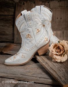 a pair of white cowboy boots next to a flower