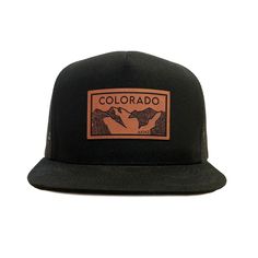 Colorado Elevation mountains faux leather patch in rawhide. Available in silver gray or black. Flat bill cotton twill front. Mesh back with adjustable snapback Black Snapback Hat For Camping, Casual Flat Brim Snapback Hat For Adventure, Black Baseball Cap For Adventure, Brown Trucker Hat With Curved Brim For Hiking, Brown Curved Brim Trucker Hat For Hiking, Adjustable Trucker Hat With Logo Patch For Camping, Outdoor Snapback Hat With Curved Brim And Embroidered Patch, Urban Trucker Hat With Logo Patch For Outdoor, Urban Trucker Hat With Logo Patch