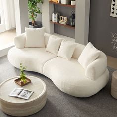 a large white couch sitting in a living room next to a table and bookshelf