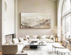 an elegant living room with white furniture and large painting hanging on the wall above it