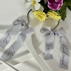 two ribbons tied to each other with name tags on them and flowers in the background