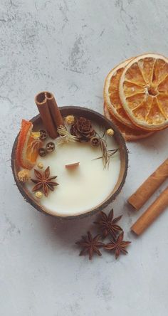 an orange slice and cinnamon sticks sit next to a glass of milk with star anise on the side