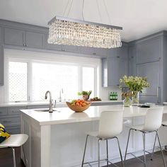 a kitchen island with chairs and a bowl of fruit on it