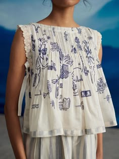 Crafted from delicate Chanderi fabric, this hand screen printed crop top features delicate lace detailing on the armholes, and a pleated neck and shoulders for a sophisticated touch. The ivory color and side tie up add elegance to this must-have piece. It comes with a cotton inner slip. Crop Shirts For Women, Pleated Crop Top, Cotton Tops Designs, Linen Style Fashion, Pleated Neck, Salwar Kamiz, Fashion Top Outfits, Pleated Top, Blouse Drafting Patterns