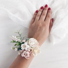 a woman's hand with flowers on her wrist and white veil in the background