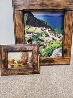 two wooden frames sitting on top of a carpeted floor next to each other with pictures in them