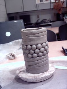 a vase made out of clay sitting on top of a table next to a laptop computer