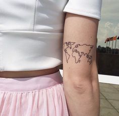 a woman's arm with a small world map tattoo on the back of her left arm