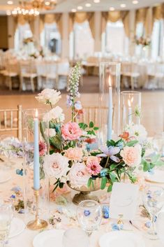 the table is set with white and pink flowers, silverware, and pictures on it