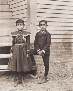 two young boys standing next to each other in front of a building with stairs and steps