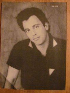 a black and white photo of a young man with dark hair, wearing a black shirt