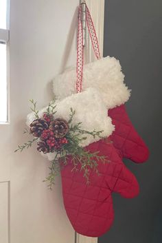 a christmas stocking hanging on the door with pine cones and greenery in it