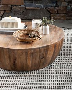 a coffee table made out of wood with candles and other items on it sitting in front of a stone wall