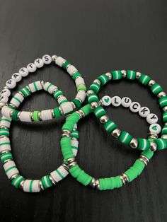 three green and white beaded bracelets sitting on top of a table