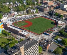 an aerial view of a baseball field in the middle of a city with buildings around it